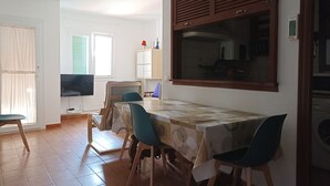 A dining area with a table, chairs, a television, and a cabinet. - Apartment 100 meters from the promenade and beach. Incredible rooftop views. (Conil de la Frontera)