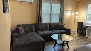 Una sala de estar con un sofá modular, una mesa de centro de vidrio y una lámpara de pie.