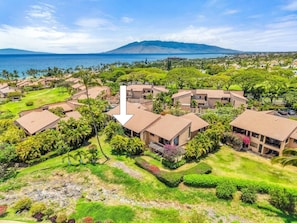 A resort with multiple buildings, a view of the ocean, and a mountain in the distance. - Dream Getaway w AC Pools Beaches Golf-WEK 40E (Kihei)