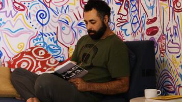 A person sitting on a couch reading a book in a room with colorful abstract wall art.