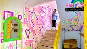 A staircase with colorful graffiti walls and a yellow door at the bottom. - Free Spirit Hostel Guadalajara (Guadalajara)