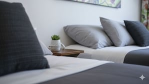 A modern hotel room with a bed, a small table with a plant, and a painting on the wall. - Free Spirit Hostel Guadalajara (Guadalajara)