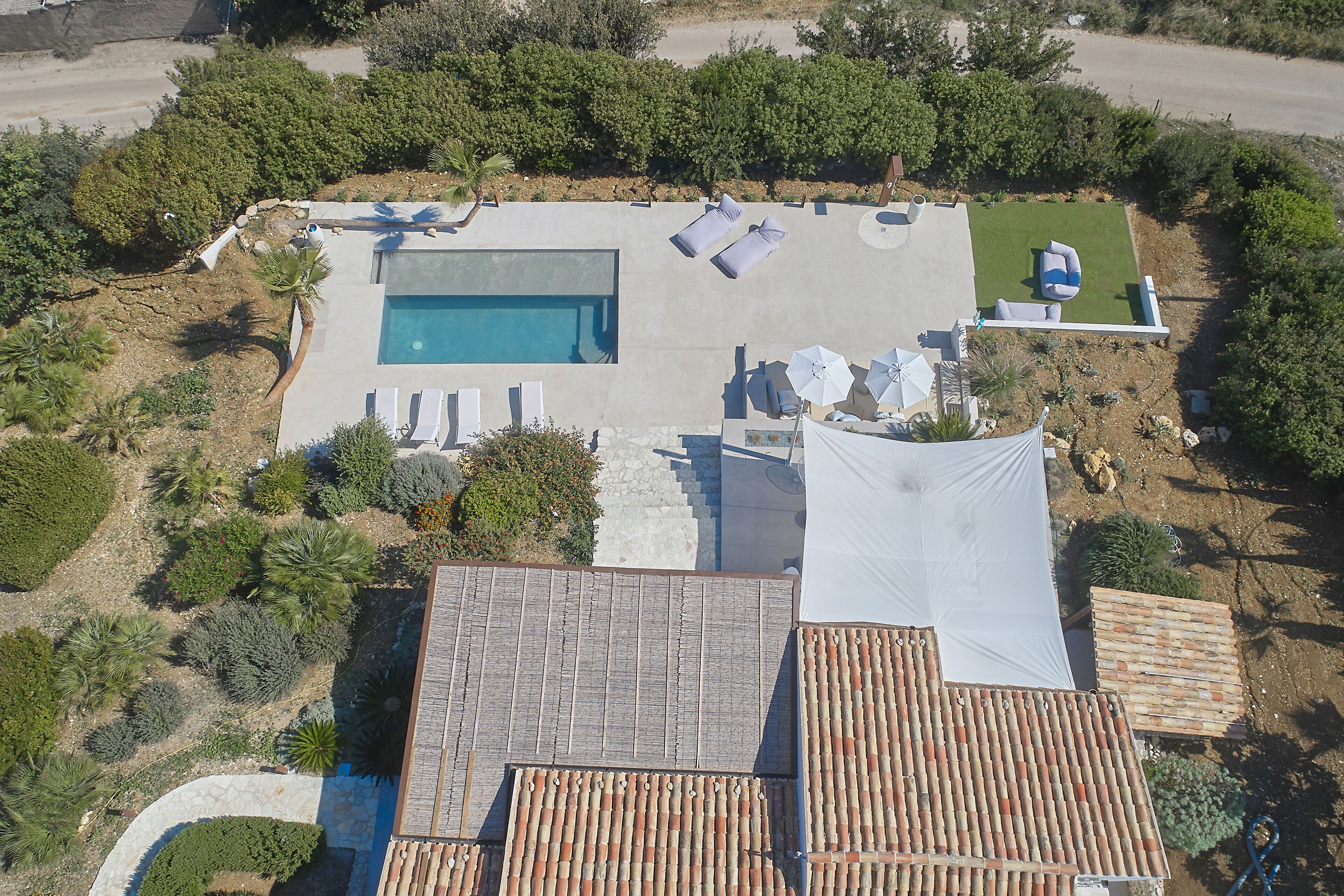 An aerial view of a property with a swimming pool, lounge chairs, and a covered patio area.