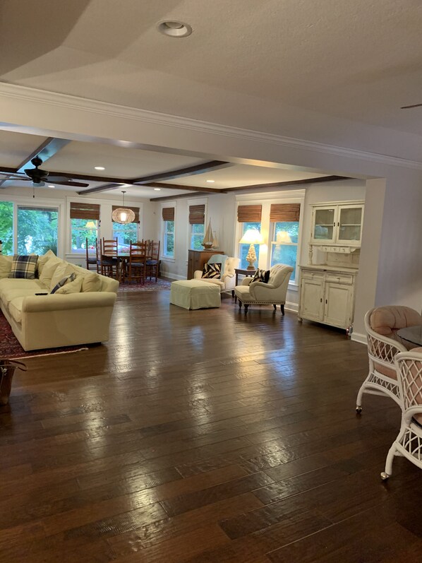 A spacious living room with a large sofa, a dining table with chairs, and a kitchen area with cabinets.