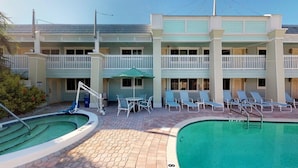 A hotel with a pool area, outdoor seating, and a two-story building with balconies. - Holmes Beach | Couples Gulf Coast Retreat | Pool + Beach (Holmes Beach)