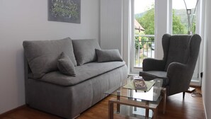 A modern living room with a grey sofa, a matching armchair, and a glass coffee table. - Vacation apartment Eder-Ufer 1 - Holiday apartments Eder-Ufer (Edertal)