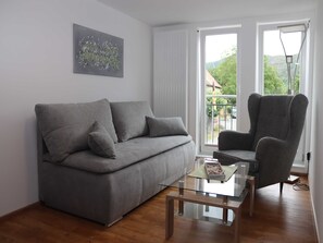 A modern living room with a grey sofa, a matching armchair, and a glass coffee table. - Vacation apartment Eder-Ufer 1 - Holiday apartments Eder-Ufer (Edertal)