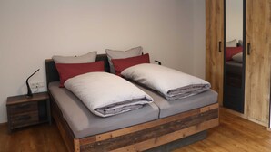 A bedroom with a wooden bed frame, a nightstand, a bedside lamp, and a wardrobe with a mirror.