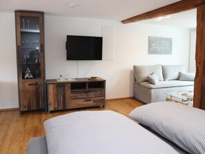 Una habitación moderna con un armario de madera, un televisor de pantalla plana, un sofá y dos camas con ropa de cama a rayas.