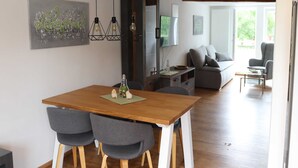 A modern dining area with a wooden table, grey upholstered chairs, and a minimalist decor.