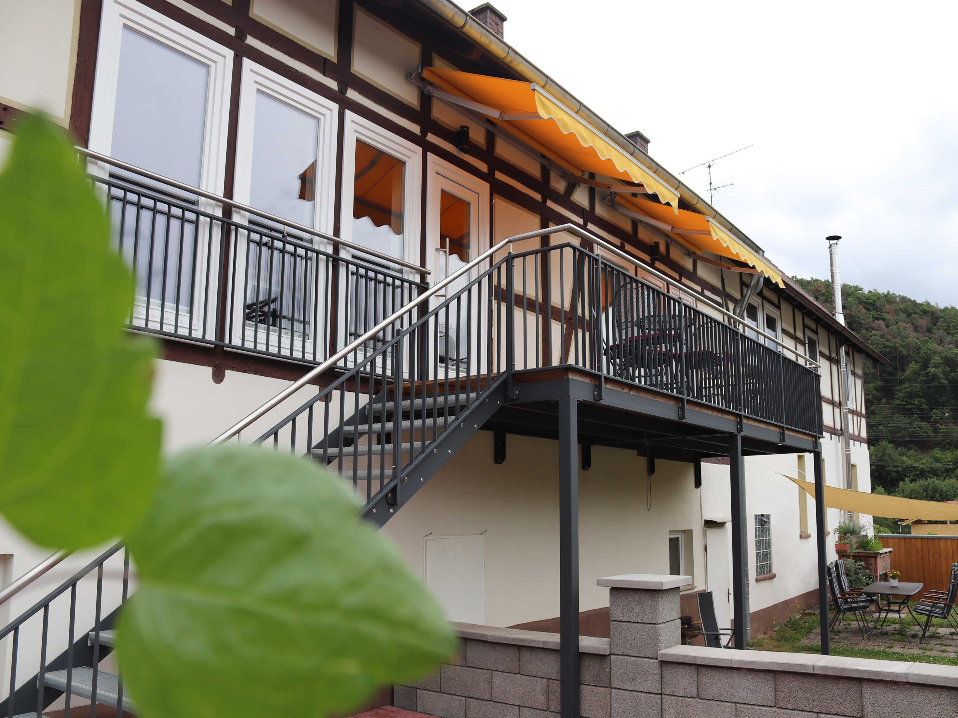 A two-story building with a balcony, a staircase, and a patio area with outdoor furniture.