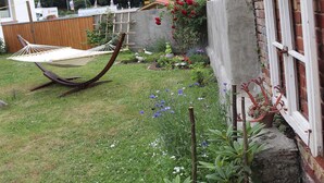 A garden with a hammock, potted plants, and a brick wall.