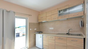 A modern kitchen with wooden cabinets, a built-in oven, and a small dishwasher. - Happy Days Home Apartment and Studio (Rhodes)