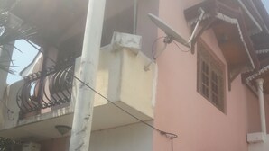 A building with a pink facade, white columns, and a balcony with a metal railing. - House with 4 beds and 2 attached bathroom.  (Wattala)