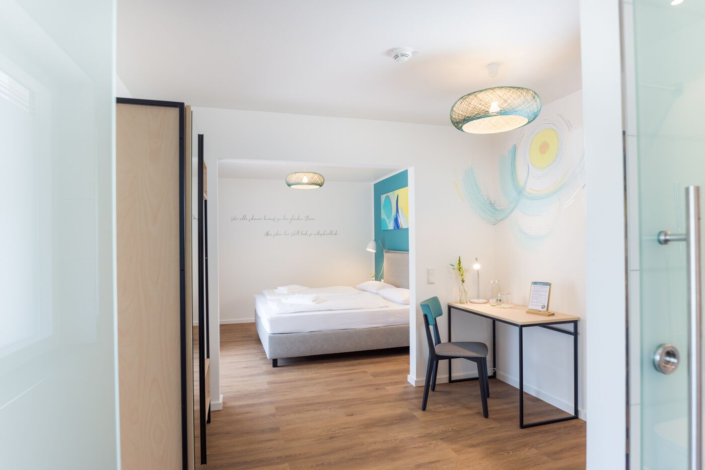 Habitación de hotel moderna con cama, escritorio y una silla. Una pared con una cita y arte abstracto.