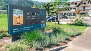 A sign for Mühlenberg Hotel II Café Restaurant with a view of the surrounding area. - Hotel & Café Mühlenglück (Oppenau)