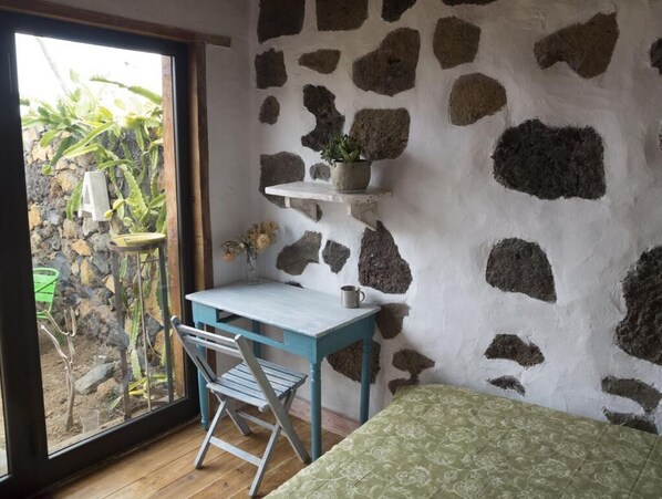 Cozy retreat with a wooden desk, potted plant, and garden view.