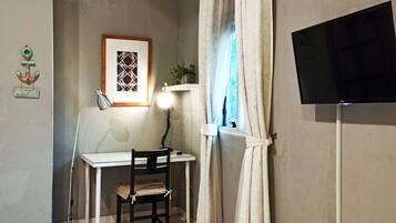 A small room with a desk, chair, lamp, and a clock on the wall.