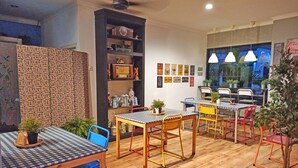 A cozy cafe with checkered tables and chairs, a bookshelf with various items, and a wall decorated with coffee-related posters. - Manggolo Homestay Syariah (Yogyakarta)