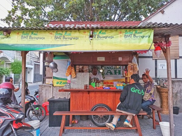 A roadside food stall with a yellow and green banner advertising BMT Beringharjo. - Manggolo Homestay Syariah (Yogyakarta)