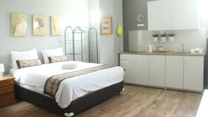 A bedroom with a bed, bedside table, and a small desk with a chair. - Manggolo Homestay Syariah (Yogyakarta)