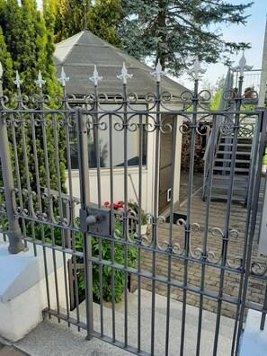 A gated area with a small structure, possibly a shed or storage, surrounded by a metal fence with decorative elements.