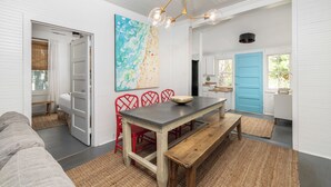 Een modern interieur met een eethoek, een groot abstract schilderij en een blauwe deur.