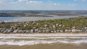 Een kustgebied met woonhuizen aan het strand, een zandstrand en een rivier of baai op de achtergrond.