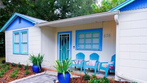 A house with a blue and white exterior, numbered 626, featuring a porch with blue chairs and potted plants.