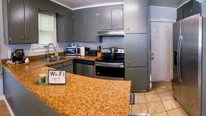 A kitchen with granite countertops, stainless steel appliances, and grey cabinets.
