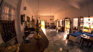 Ein traditionell eingerichteter Raum mit Schachbrettfußboden, Holzmöbeln und einer großen Messinglampe.
