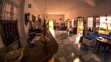 Ein traditionell eingerichteter Raum mit Schachbrettfußboden, Holzmöbeln und einer großen Messinglampe.
