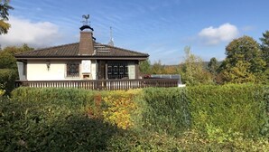 A building with a sloped roof, a chimney, and a fenced porch. - House with lake view and terraces - spacious (Edertal - Bringhausen)