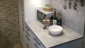A kitchen with a microwave, a bowl, two salt shakers, a bottle of champagne, and a set of keys on the counter. - House with lake view and terraces - spacious (Edertal - Bringhausen)