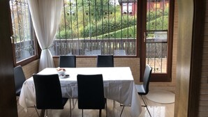 A dining area with a table set for four, a view of a garden through a window, and a door leading outside. - House with lake view and terraces - spacious (Edertal - Bringhausen)
