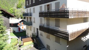 Ein mehrgeschossiges Gebäude mit Balkonen, einer Treppe und einer kleinen Gartenanlage.