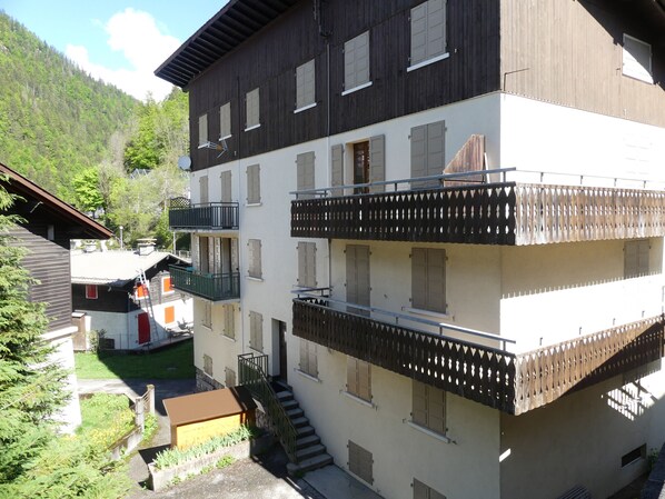 A multi-story building with balconies, a staircase, and a small garden area.