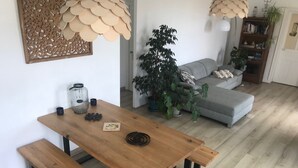 A dining area with a wooden table and benches, a decorative wall piece, and a potted plant. - Two bedrooms for six people, swimming pool in Hérault (Roujan)