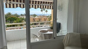 En balkon med udsigt til palmer og en strand.
