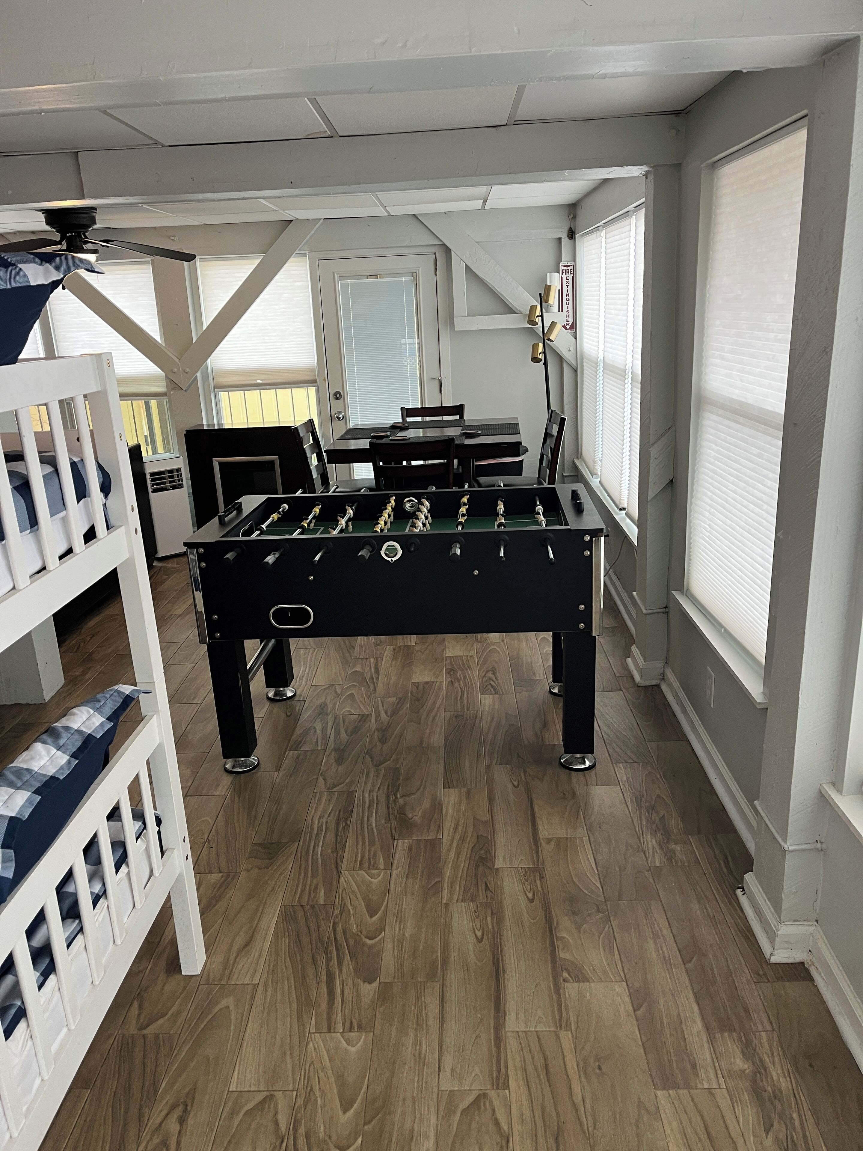 A room with a foosball table, a bunk bed, and a ceiling fan.