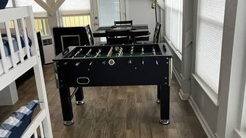A room with a foosball table, a bunk bed, and a ceiling fan.