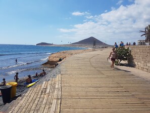 A wooden boardwalk along a beach with people and kites in the background. - Apartment Barraquito, balcony with sea view, close to the beach, wifi, ideal for surfers (El Médano)