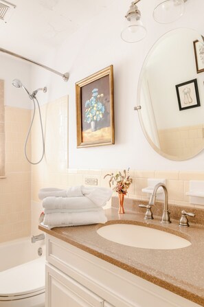 Un baño con lavamanos, inodoro, ducha y toallero.