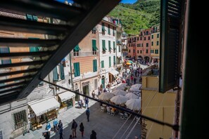 Une rue animée, bordée d’immeubles, avec des terrasses et des passants.