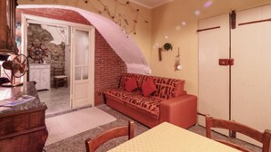 Un salon chaleureux avec un canapé, une table à manger et un coin cuisine visible à travers une arche.