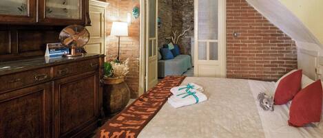 Une chambre d’hôtel avec un lit, une commode en bois, une lampe et un mur décoratif.