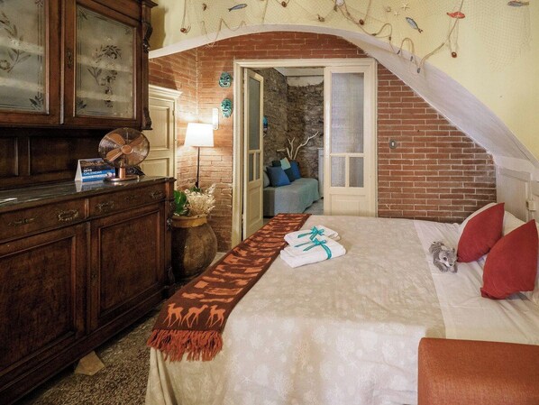Een hotelkamer met een bed, een houten dressoir, een lamp en decoratieve wanddecoratie.