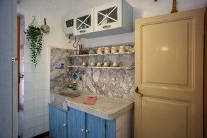 Une cuisine avec des plans de travail en marbre, des armoires bleues et une porte beige.