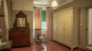 A room with a wooden dresser, a rocking chair, and a large white wardrobe.