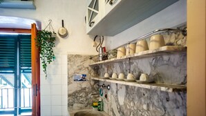 Une cuisine aux murs de marbre, avec un évier et des étagères remplies de tasses et d’assiettes.